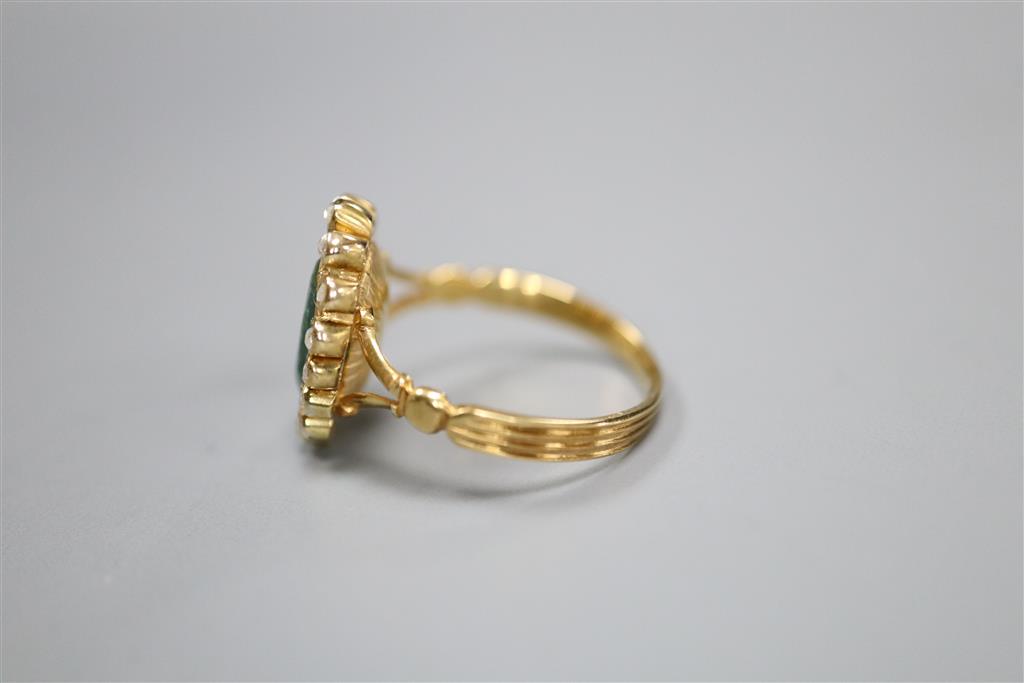 An early 20th century yellow metal, emerald and diamond set oval cluster ring, size M, gross 4 grams (emerald badly chipped).